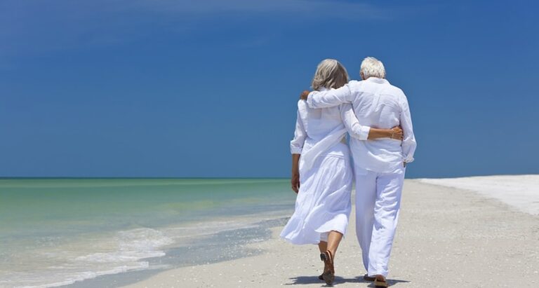 Older Couple Walking On A Deserted Beach