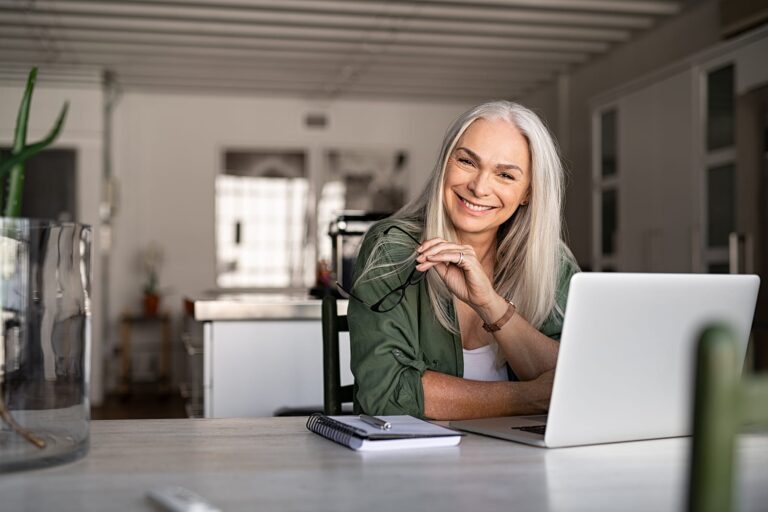 Smiling Woman Sitting At Home With Her Laptop