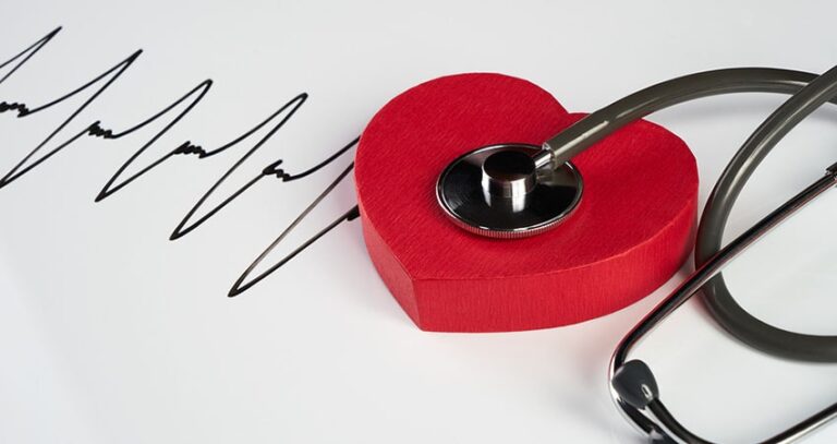 A Stethoscope On A Red Heart Next To A Drawn Electrocardiograph