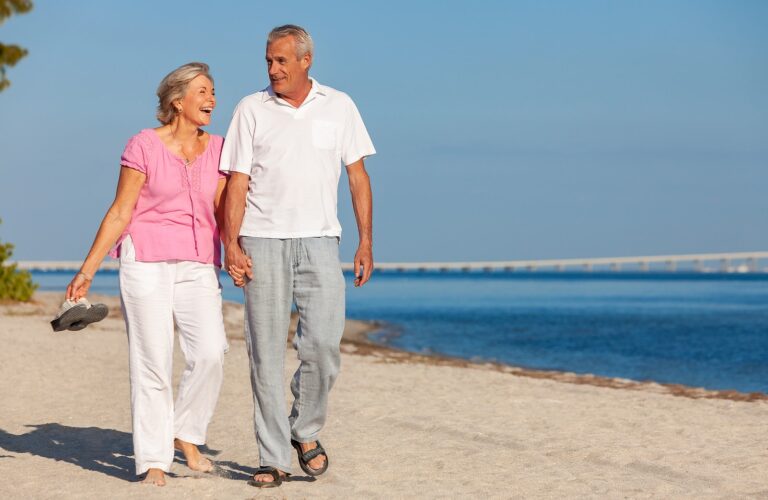 Happy Older Man And Woman Walking On The Beach