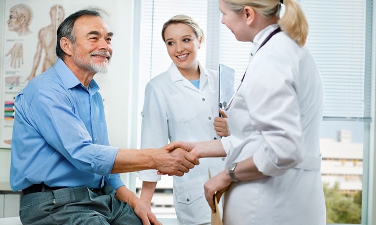 Man Shaking Hands With Doctor While Nurse Looks On