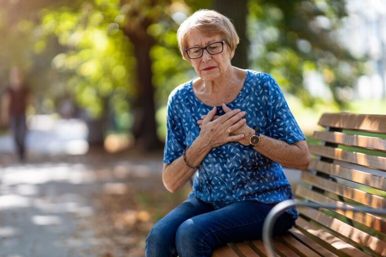 Woman In Distress Holding Her Heart Sitting On A Park Bench